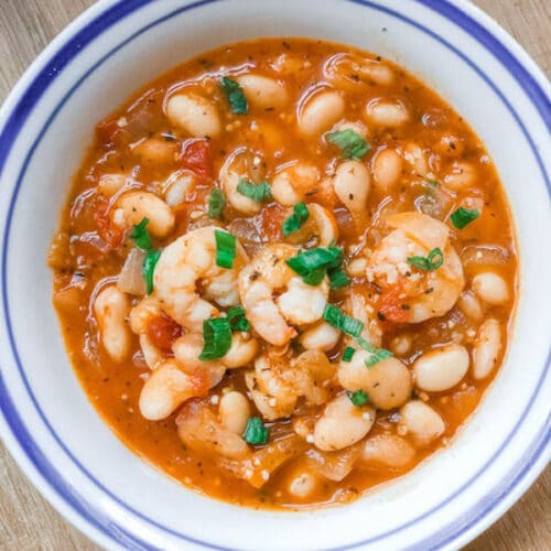 white bean and shrimp soup in a white ball on a wooden table