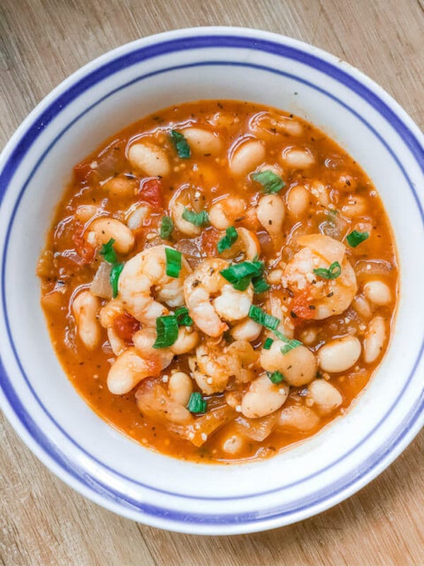 white bean and shrimp soup in a white ball on a wooden table