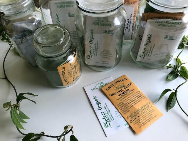 multiple glass jars with packets of seeds in each jar multiple glass jars with packets of seeds in each jar
