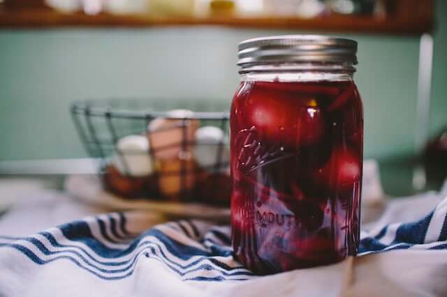 a mason jar filled with juice and eggs in a basket in the background
